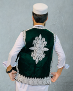 Man wearing a green embroidered vest against a gray background