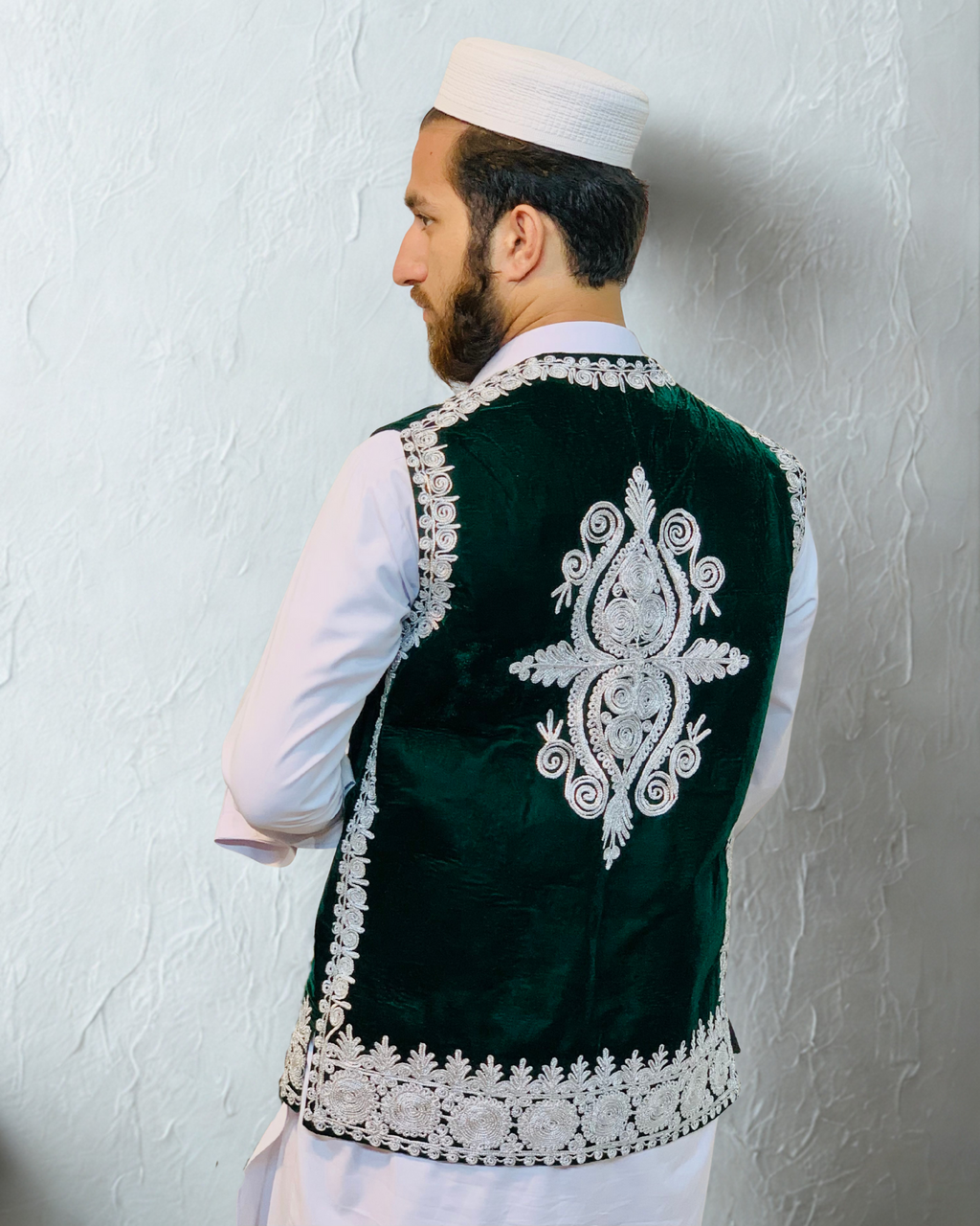 Man wearing a green embroidered vest against a plain background