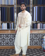 Man wearing a traditional outfit in front of a fabric display