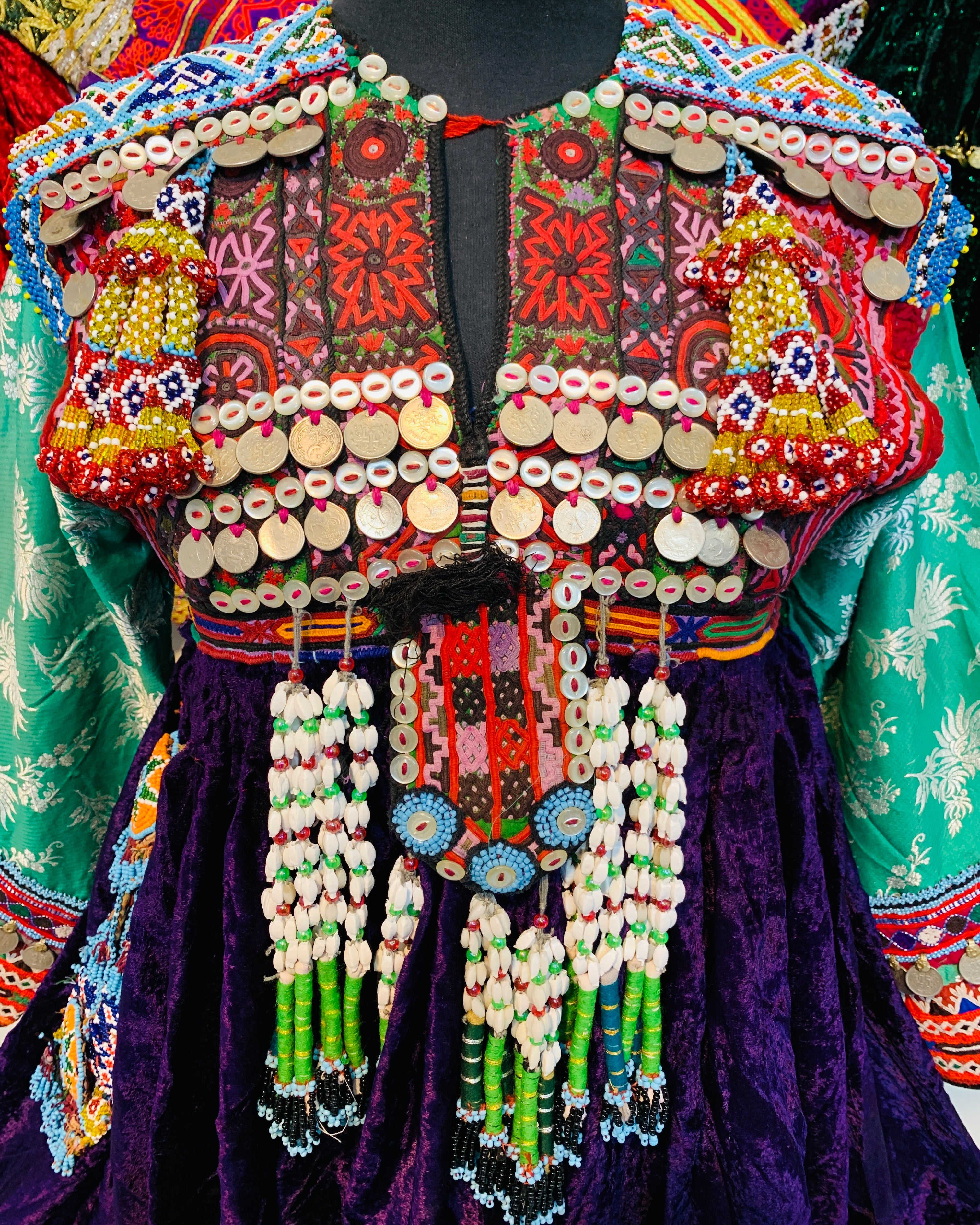 Colorful embroidered garment with intricate patterns and beadwork on a mannequin.