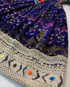Close-up of a blue patterned fabric with intricate white embroidery on a white background