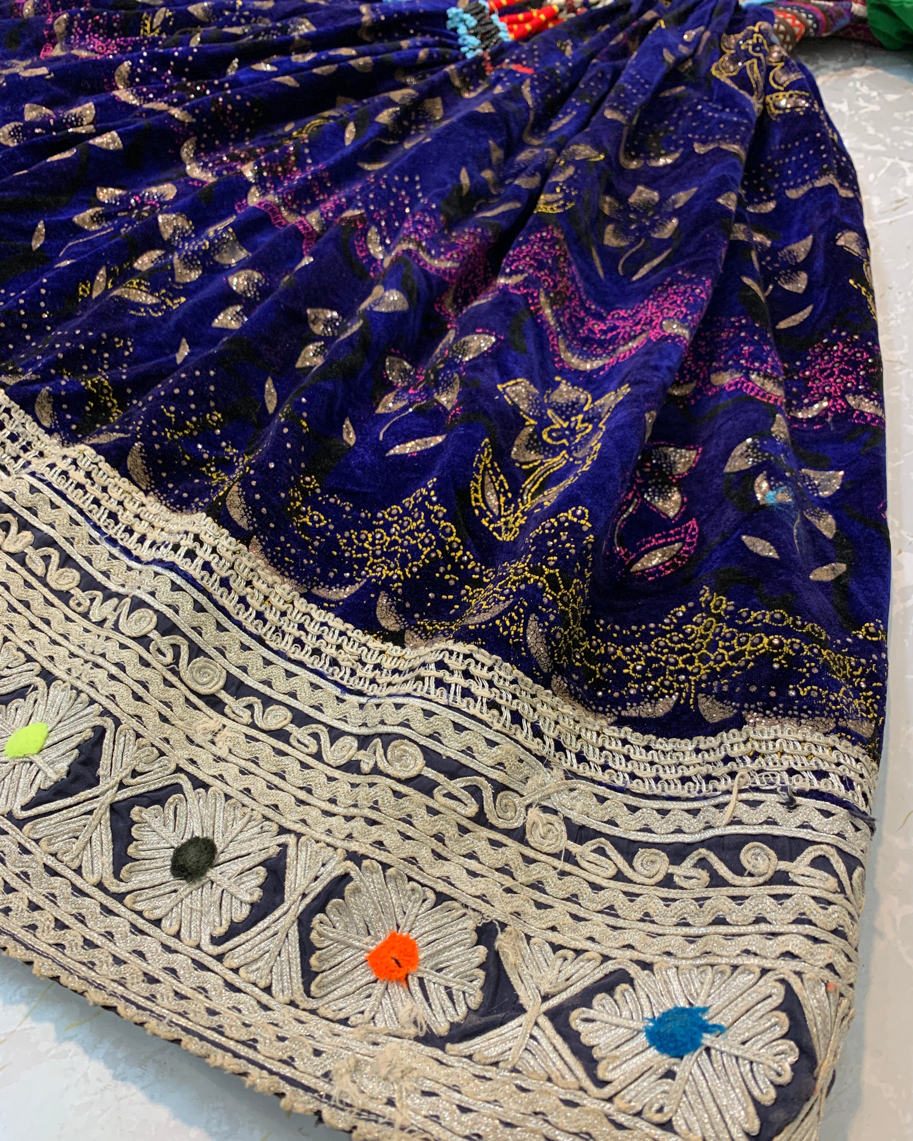 Close-up of a blue patterned fabric with intricate white embroidery on a white background