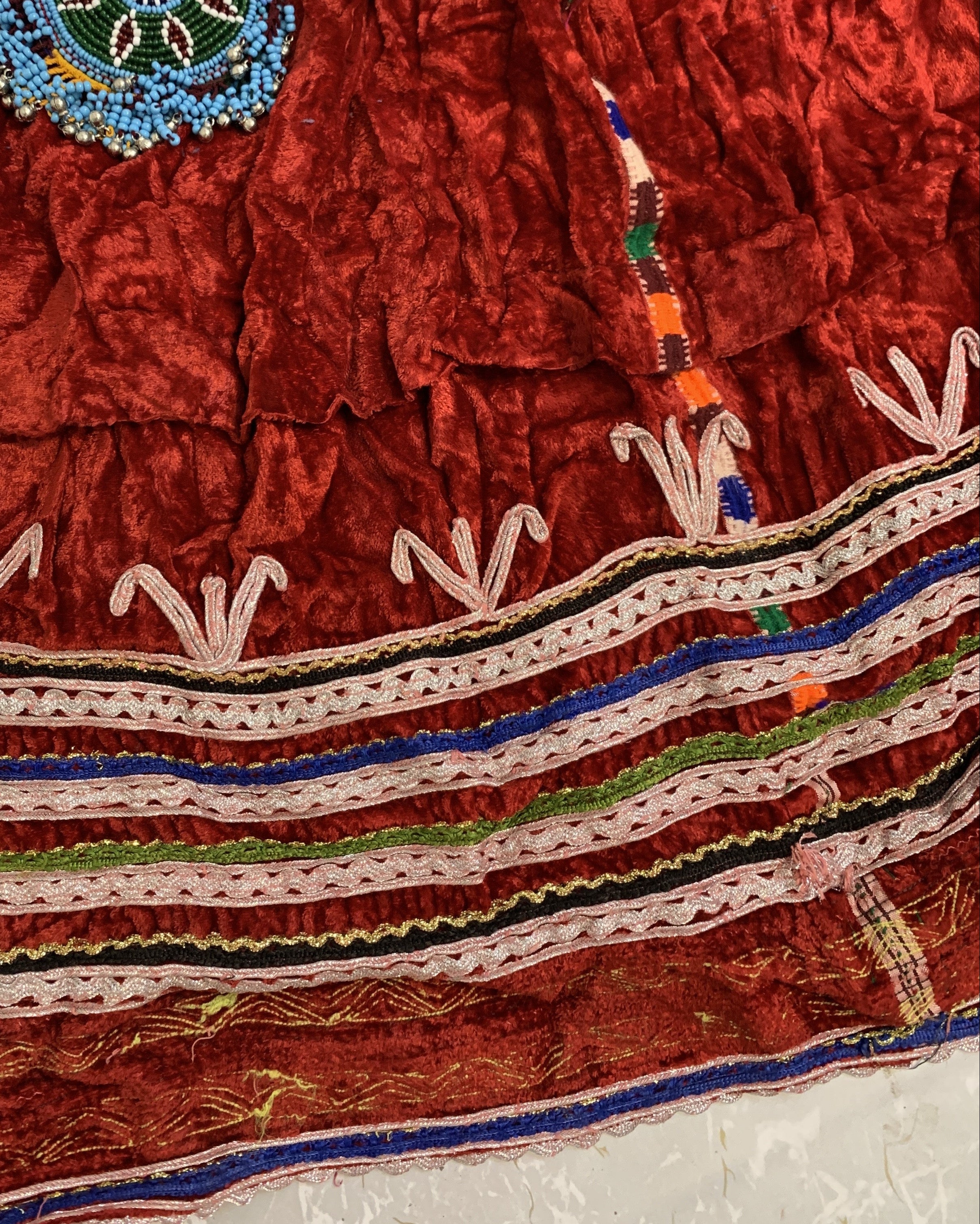 Close-up of a red embroidered fabric with intricate patterns on a textured white background