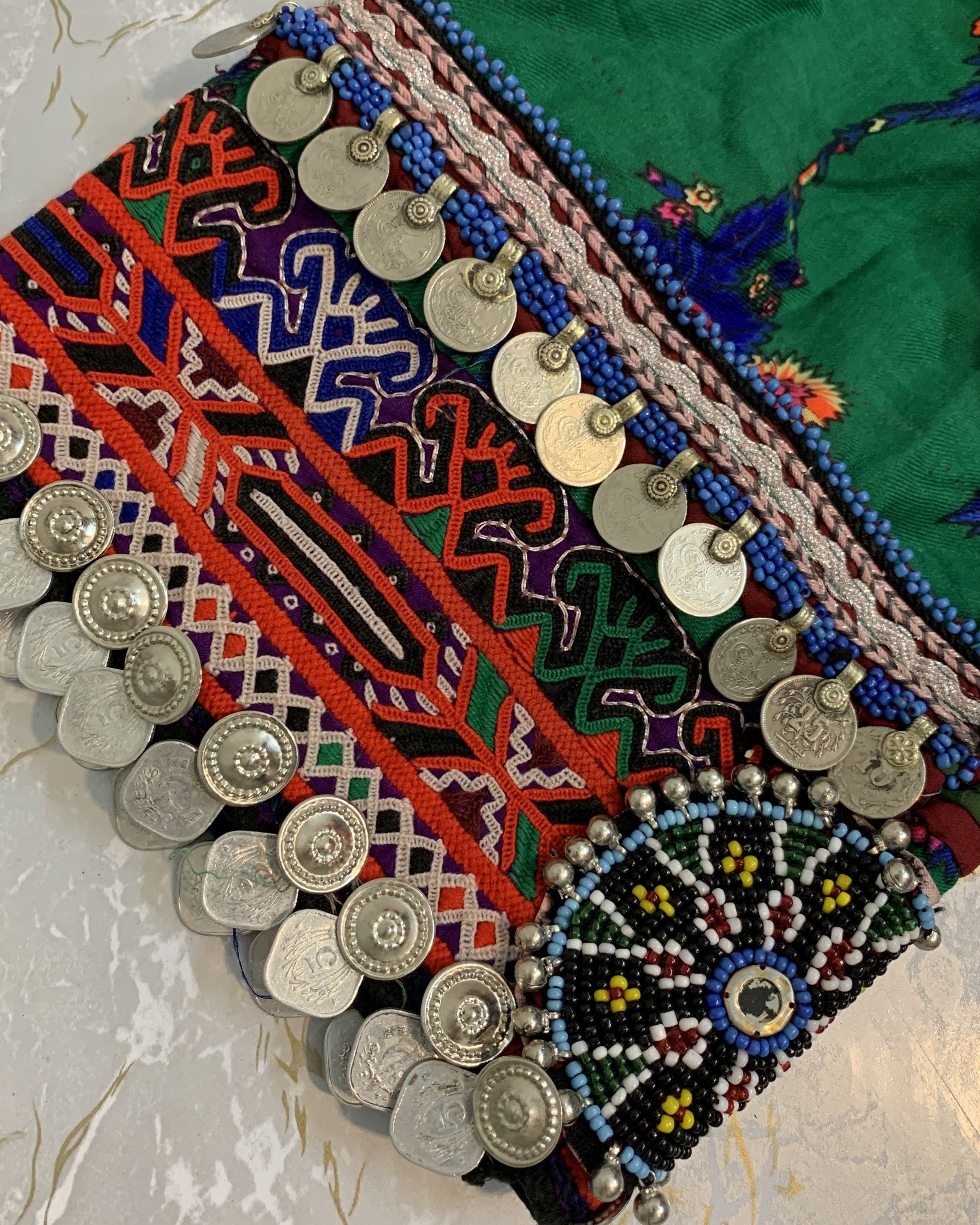 Colorful embroidered fabric with intricate patterns and decorative elements on a textured surface.