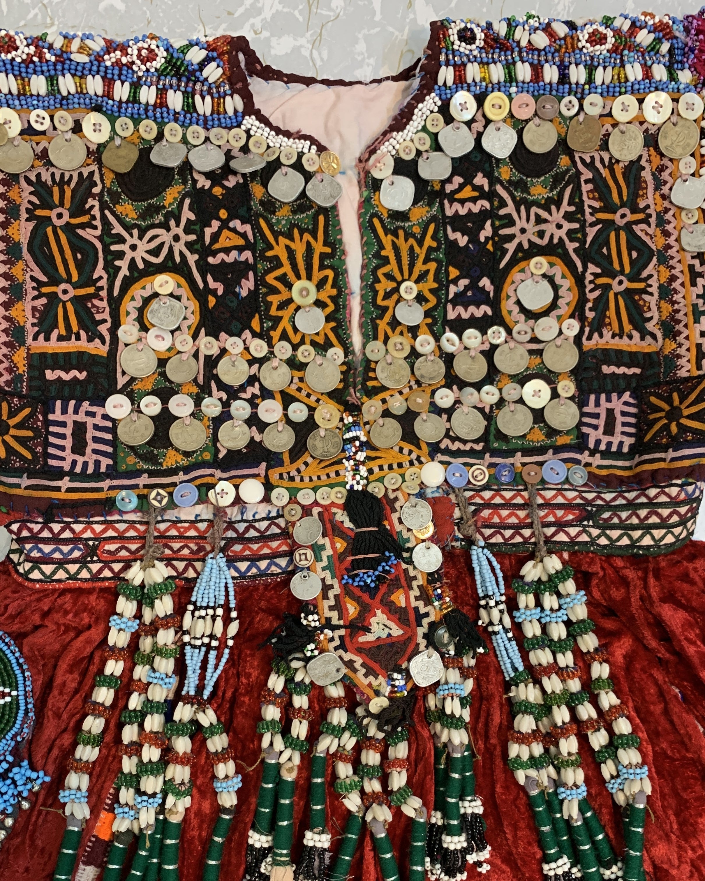 Colorful embroidered garment with intricate patterns and beadwork on a textured background