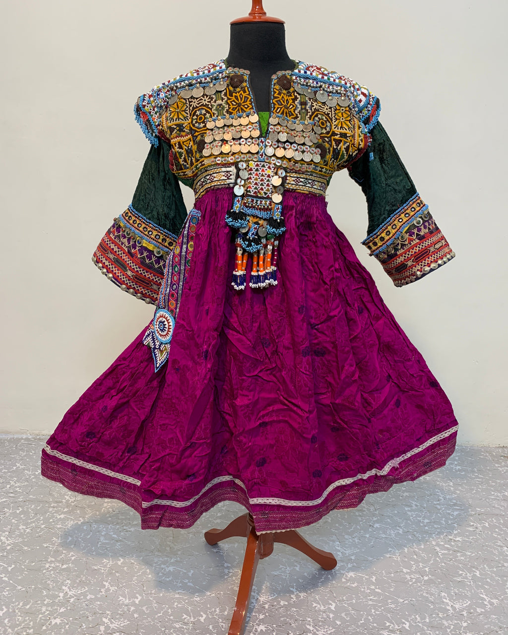 Traditional embroidered outfit on a mannequin against a textured white background