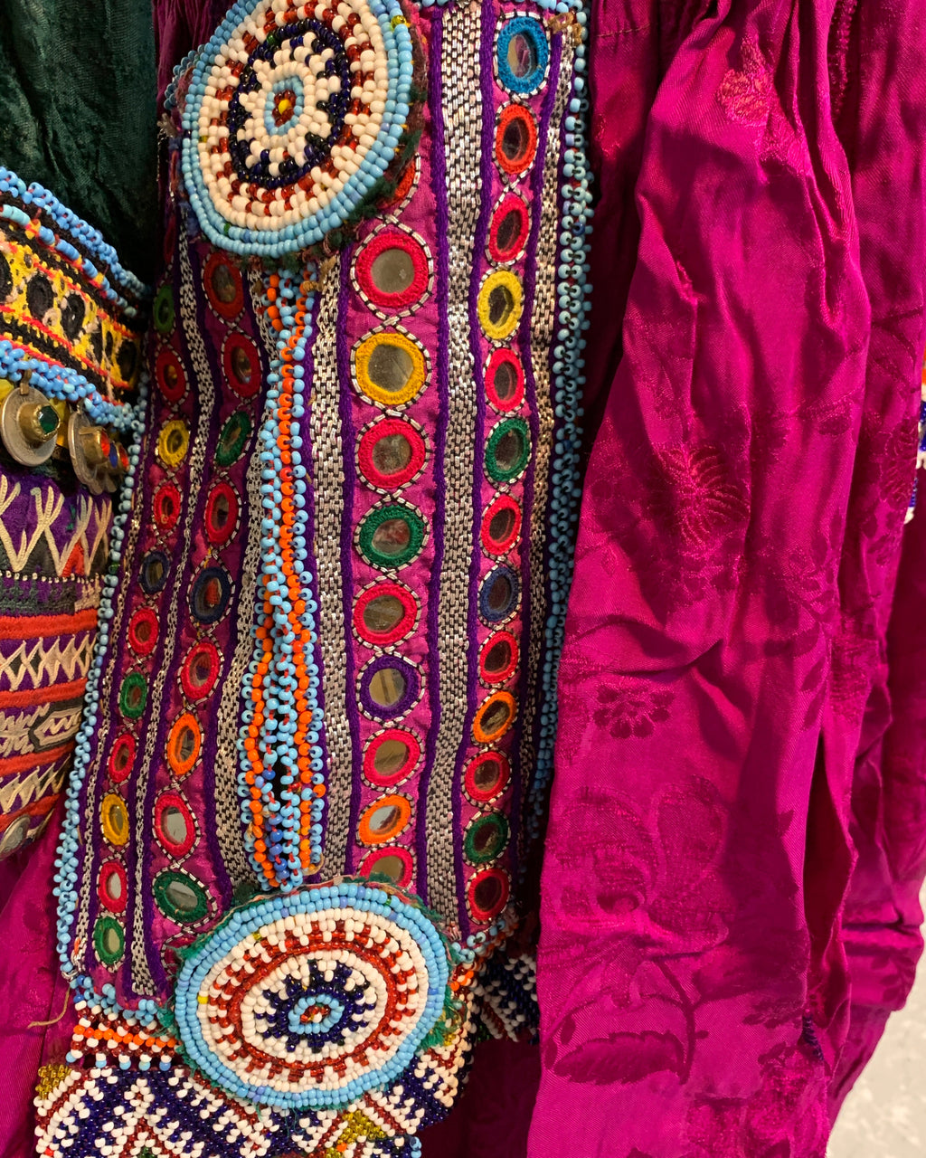 Colorful embroidered fabric with intricate patterns on a pink background