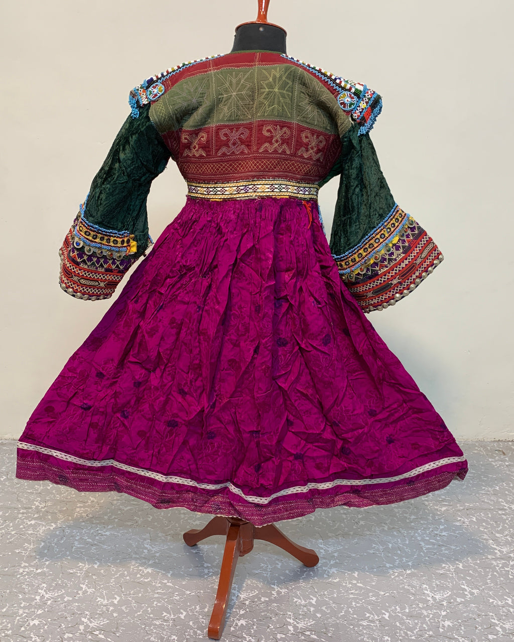 Traditional outfit with a purple skirt and green top on a mannequin against a white background