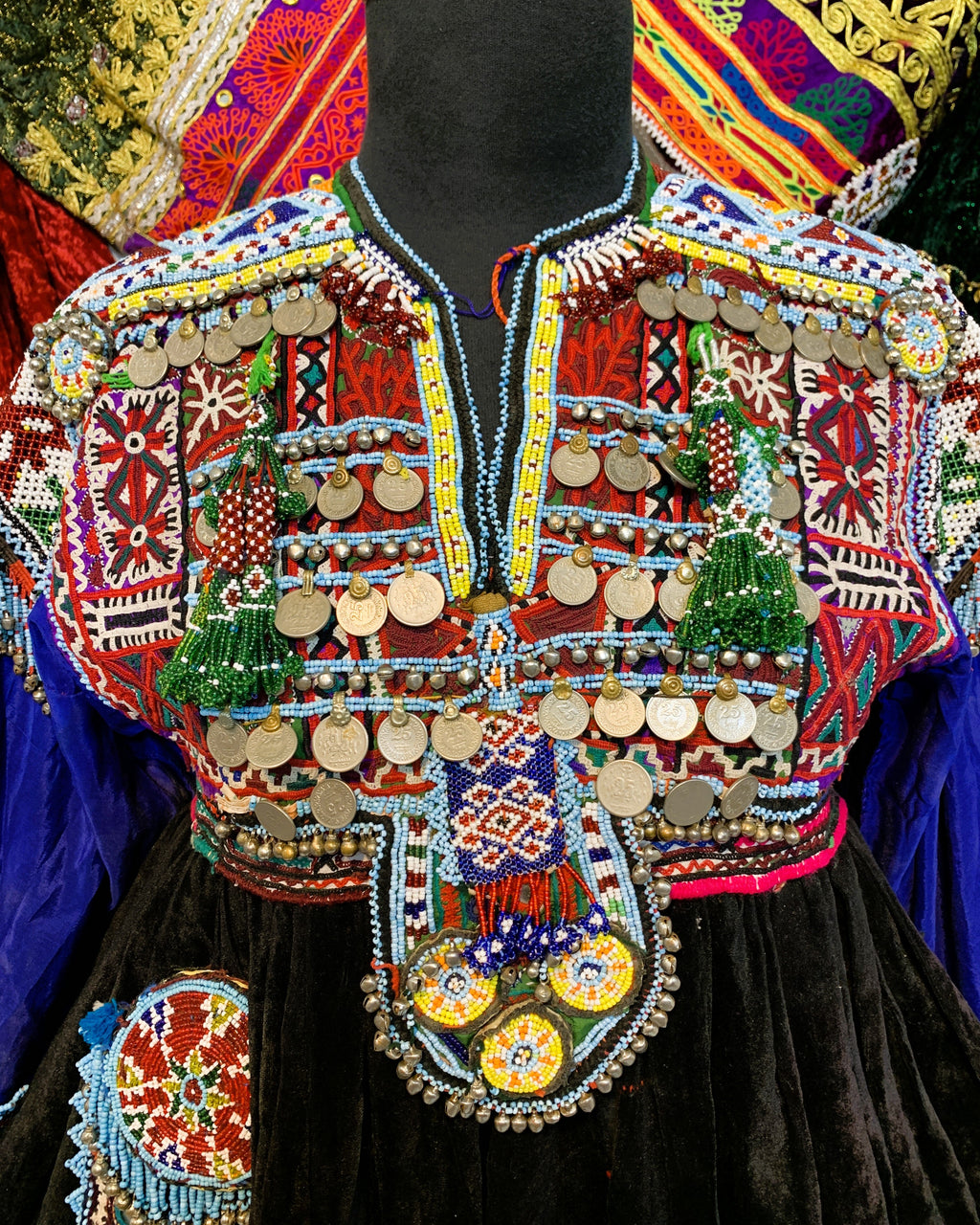 Colorful embroidered jacket with intricate patterns on a mannequin against a vibrant background.
