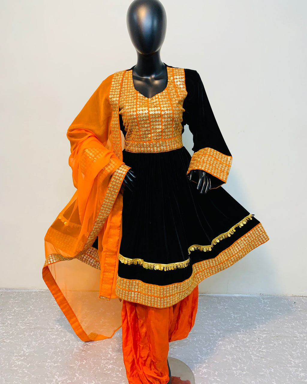 Black and orange traditional outfit on a mannequin against a white background