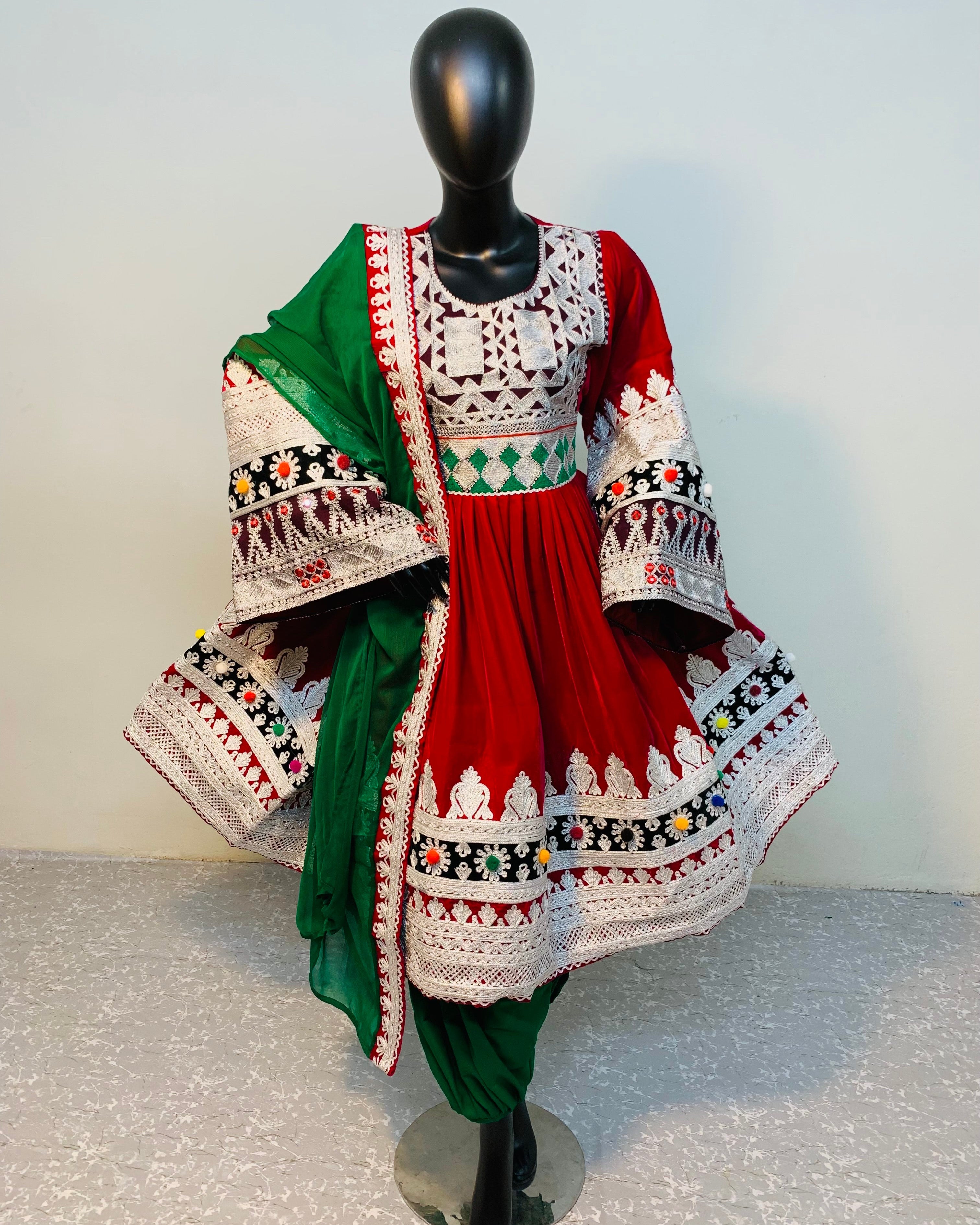 Traditional outfit with a red and green dress on a mannequin against a plain background
