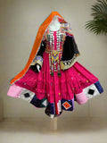 Colorful traditional outfit with a pink skirt and decorative elements on a mannequin against a backdrop of other traditional garments.