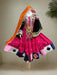 Colorful traditional outfit with a pink skirt and decorative elements on a mannequin against a backdrop of other traditional garments.