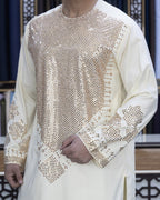 Person wearing a cream-colored traditional outfit with intricate patterns.