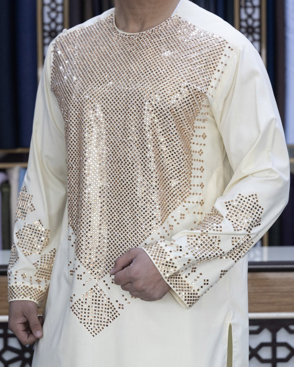 Person wearing a cream-colored traditional outfit with intricate patterns.
