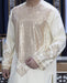 Person wearing a cream-colored traditional outfit with intricate patterns.