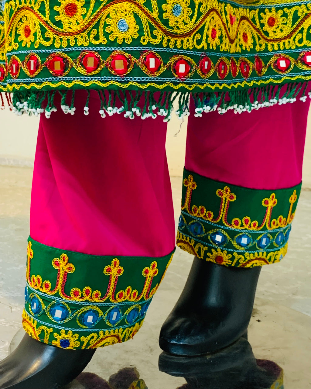 Colorful traditional outfit with embroidery and bright colors on a wooden floor.