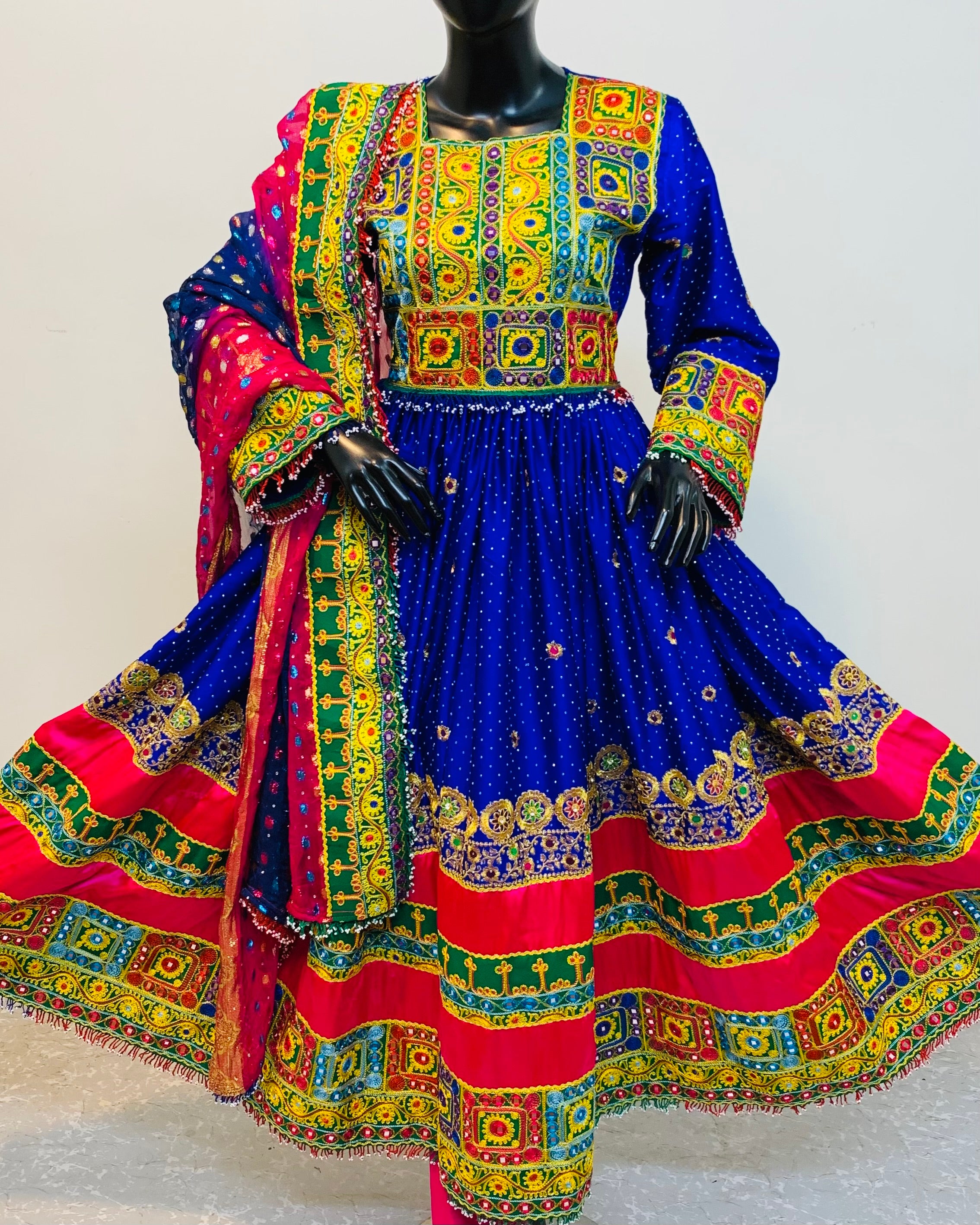 Colorful traditional outfit with a blue and red dress on a mannequin against a white background