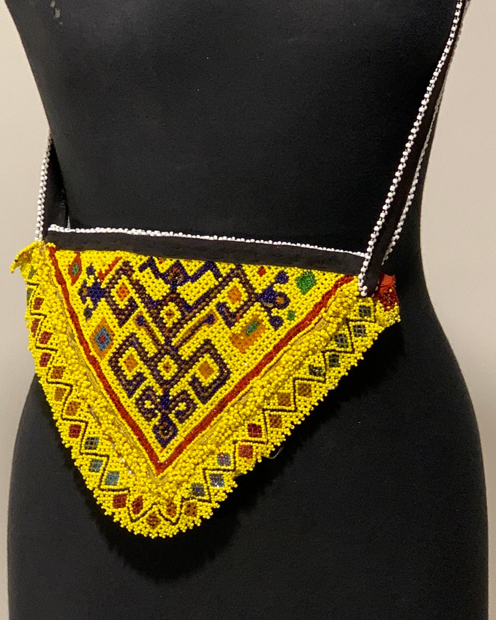 Yellow and black patterned bag on a mannequin against a beige background